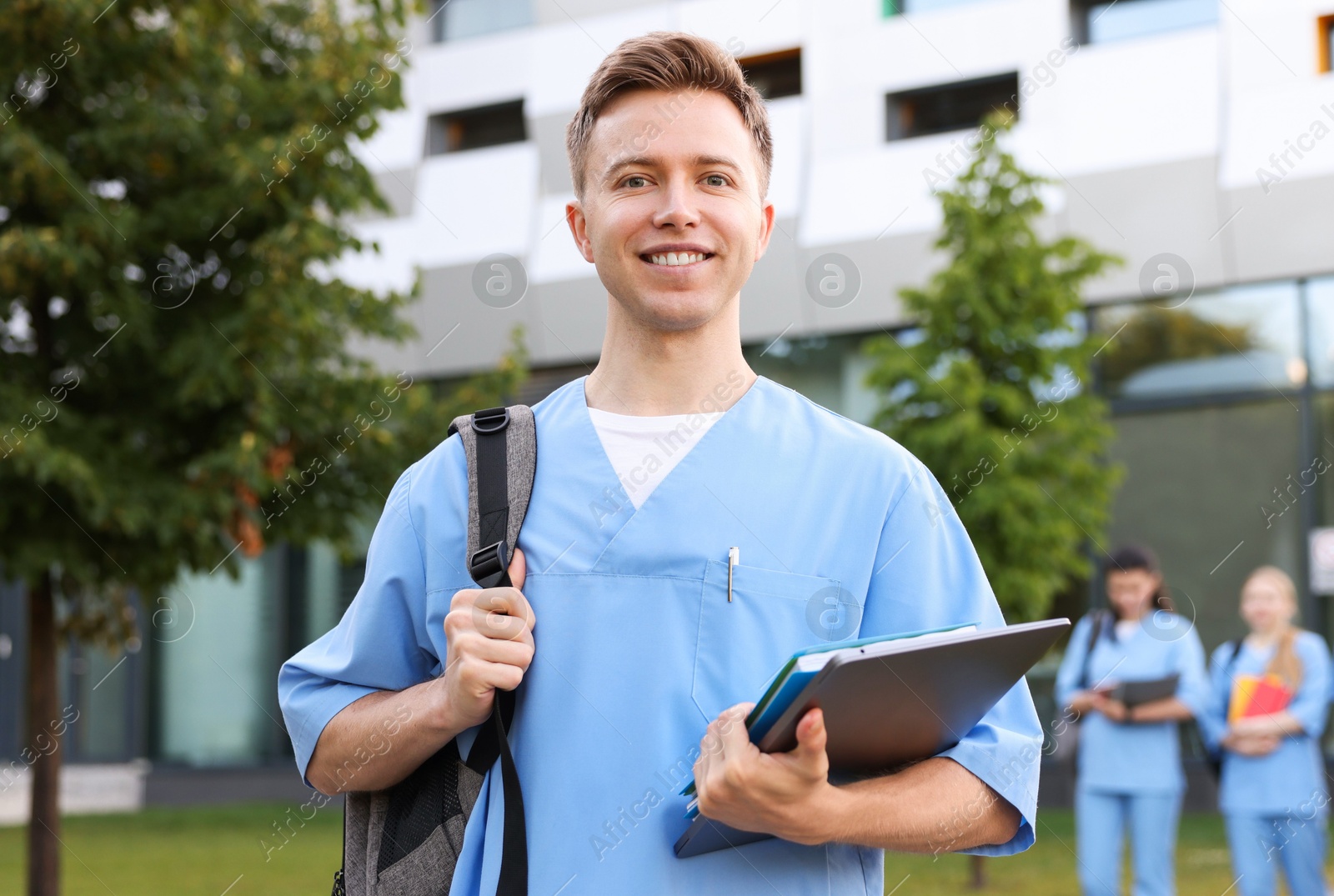 Medical student in uniform with backpack, laptop and notebook outdoors, selective focus Photo of Medical student in uniform with backpack, laptop and notebook outdoors, selective focus