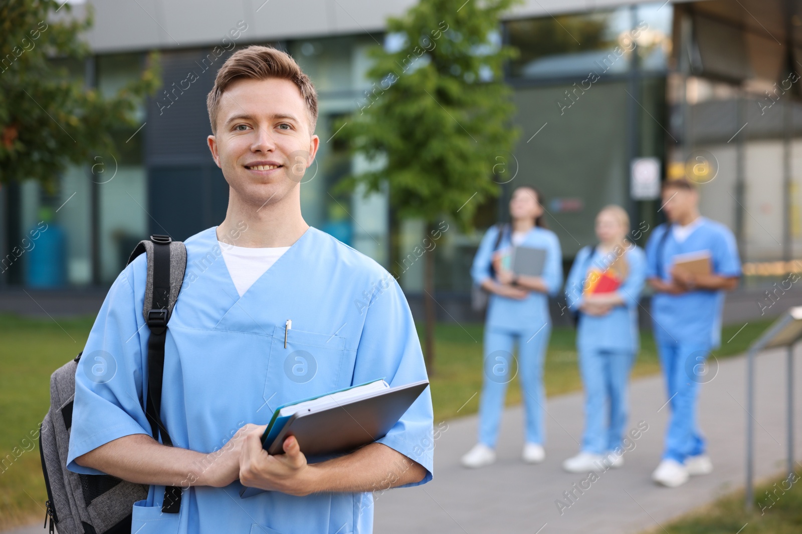 Medical student in uniform with backpack, laptop and notebook outdoors, selective focus Photo of Medical student in uniform with backpack, laptop and notebook outdoors, selective focus