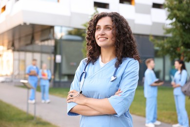 Photo of Medical student in uniform with stethoscope outdoors, selective focus