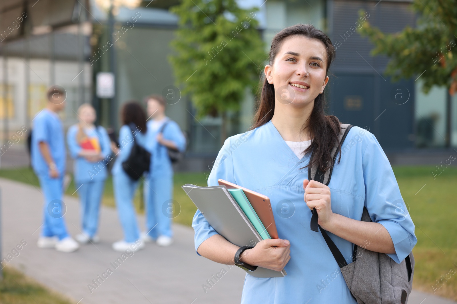 Medical student in uniform with backpack and notebooks outdoors, selective focus Photo of Medical student in uniform with backpack and notebooks outdoors, selective focus
