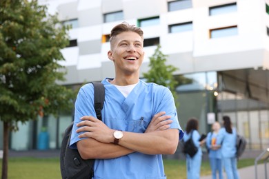 Photo of Medical student in uniform with backpack outdoors, selective focus