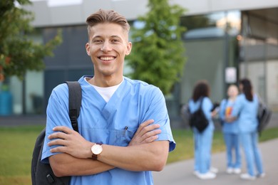 Photo of Medical student in uniform with backpack outdoors, selective focus