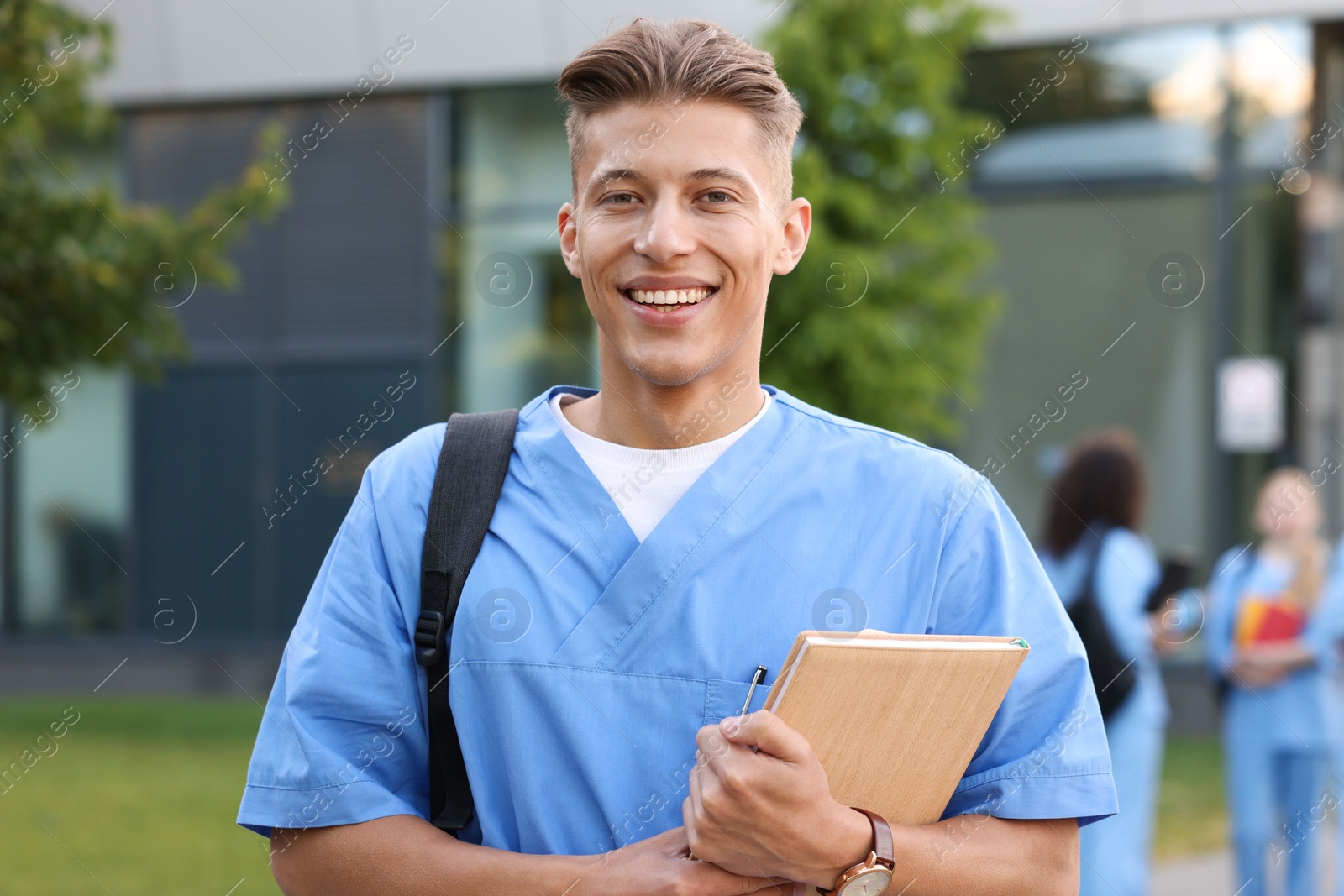 Medical student in uniform with backpack and notebook outdoors, selective focus Photo of Medical student in uniform with backpack and notebook outdoors, selective focus