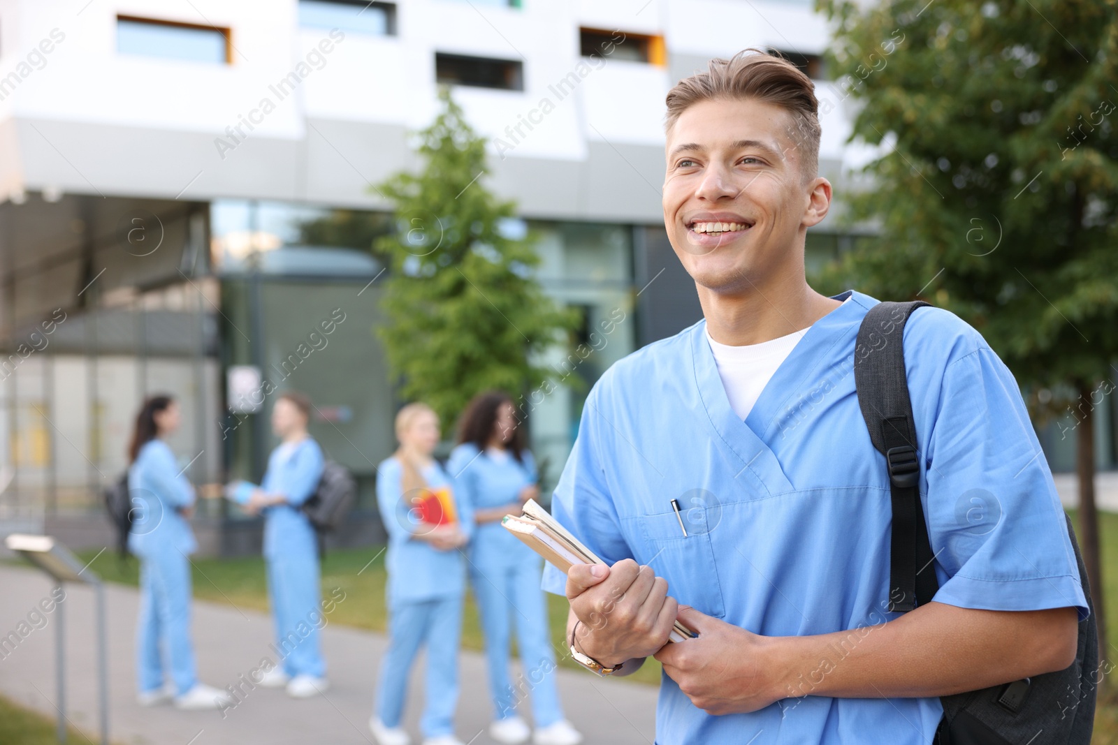 Medical student in uniform with backpack and notebooks outdoors, selective focus Photo of Medical student in uniform with backpack and notebooks outdoors, selective focus