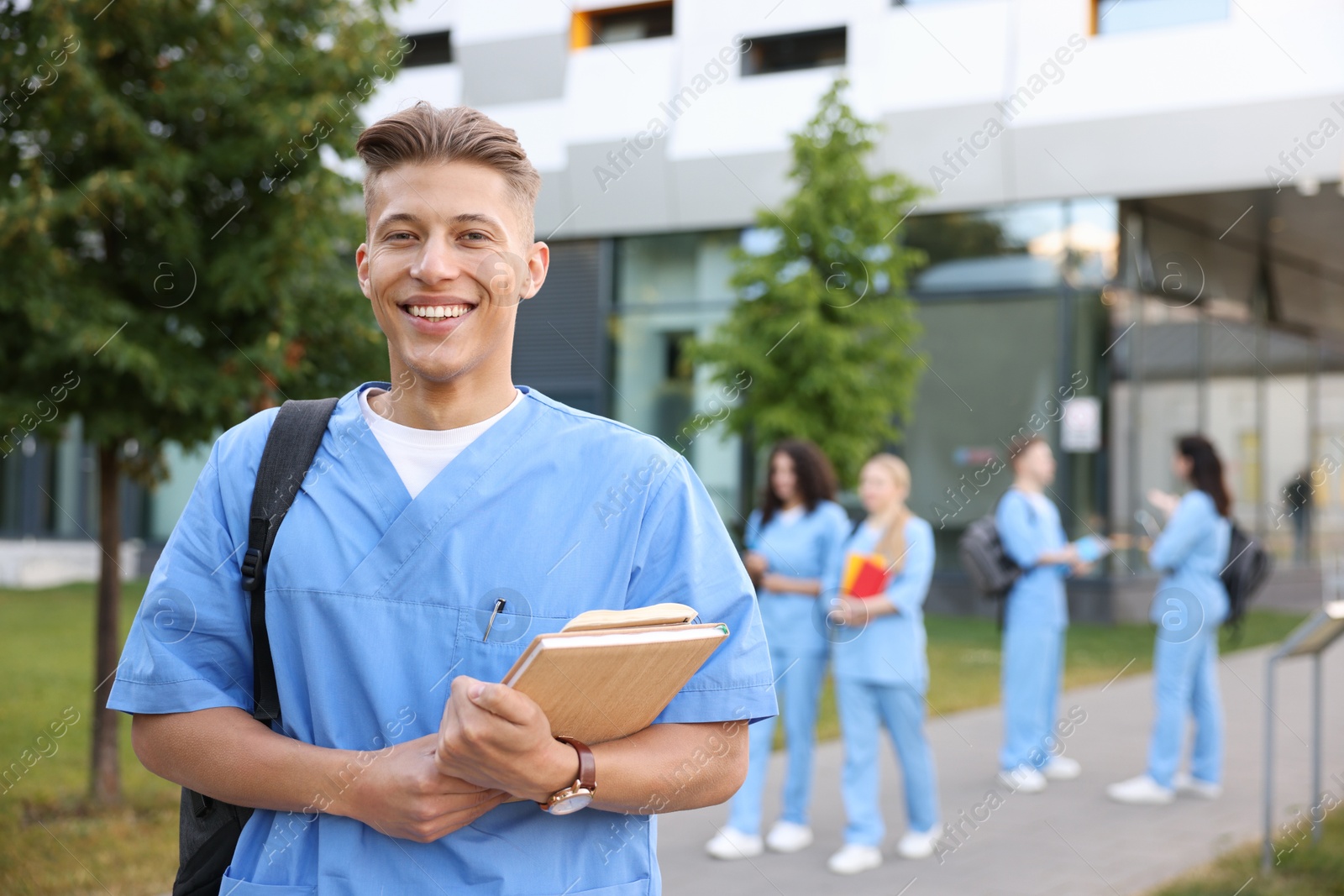 Medical student in uniform with backpack and notebooks outdoors, selective focus Photo of Medical student in uniform with backpack and notebooks outdoors, selective focus