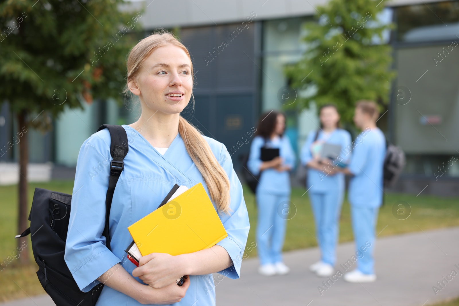 Medical student in uniform with backpack and notebooks outdoors, selective focus Photo of Medical student in uniform with backpack and notebooks outdoors, selective focus