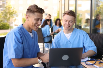 Photo of Medical students studying together in outdoor cafe, selective focus