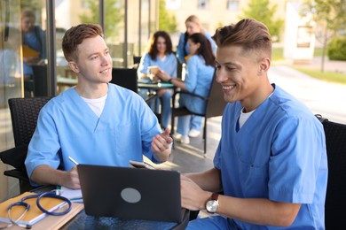 Photo of Medical students studying together in outdoor cafe, selective focus