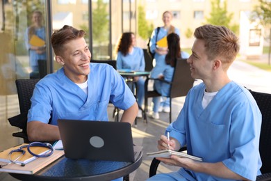 Photo of Medical students studying together in outdoor cafe, selective focus