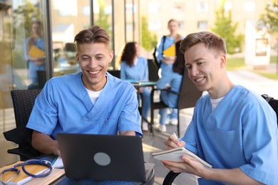 Photo of Medical students studying together in outdoor cafe, selective focus