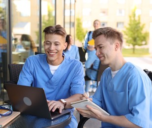 Photo of Medical students studying together in outdoor cafe, selective focus