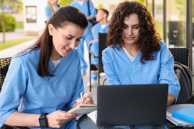 Photo of Medical students studying together in outdoor cafe, selective focus
