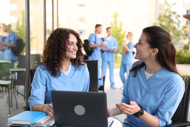 Photo of Medical students studying together in outdoor cafe, selective focus