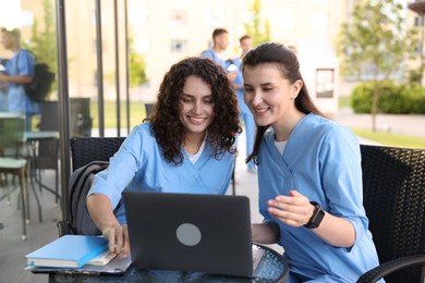 Photo of Medical students studying together in outdoor cafe, selective focus