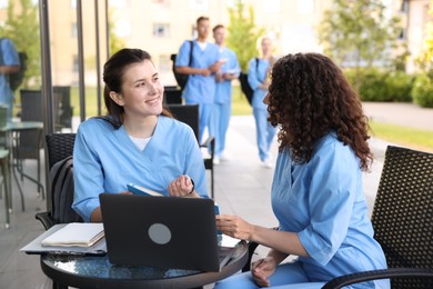 Photo of Medical students studying together in outdoor cafe, selective focus