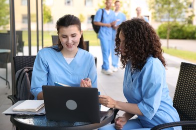 Photo of Medical students studying together in outdoor cafe, selective focus