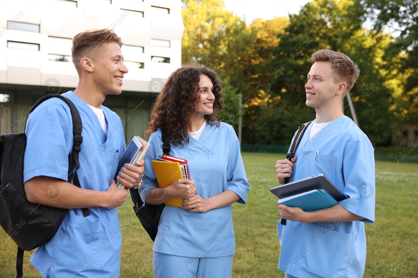 Photo of Medical students in uniforms with backpacks and notebooks outdoors