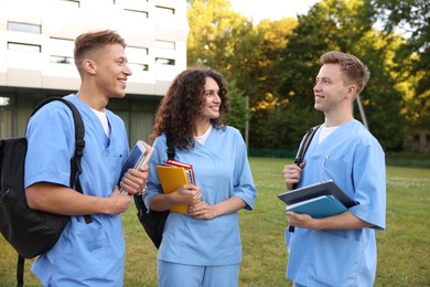 Photo of Medical students in uniforms with backpacks and notebooks outdoors