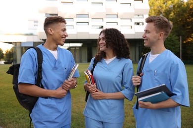 Photo of Medical students in uniforms with backpacks and notebooks outdoors
