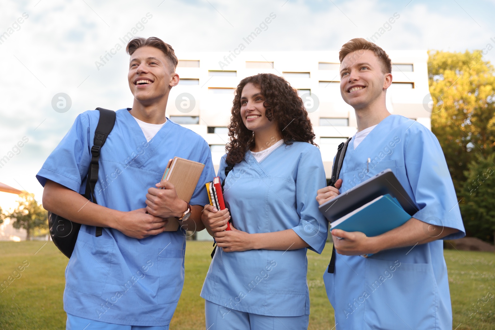 Medical students in uniforms with backpacks and notebooks outdoors Photo of Medical students in uniforms with backpacks and notebooks outdoors
