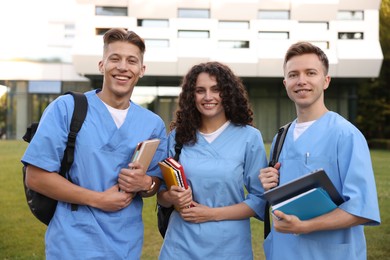 Photo of Medical students in uniforms with backpacks and notebooks outdoors