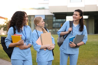 Photo of Medical students in uniforms with backpacks and notebooks outdoors