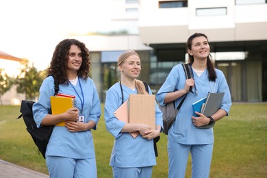 Photo of Medical students in uniforms with backpacks and notebooks outdoors