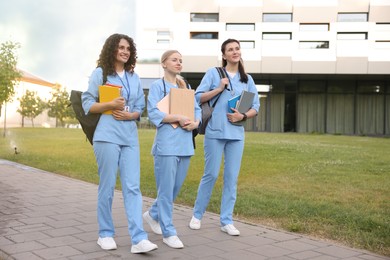 Photo of Medical students in uniforms walking near building outdoors