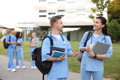 Photo of Medical students in uniforms with backpacks and notebooks outdoors, selective focus
