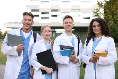 Photo of Medical students in uniforms with backpacks and notebooks outdoors, selective focus