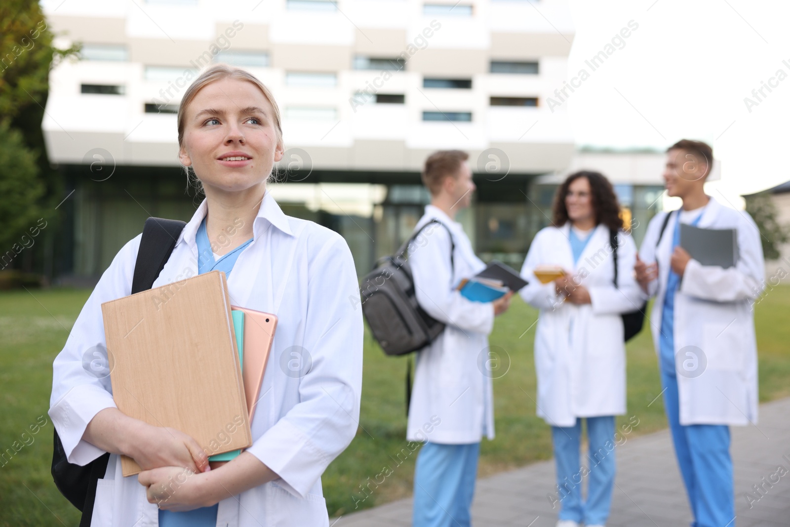 Medical student in uniform with backpack, tablet and notebooks outdoors, selective focus Photo of Medical student in uniform with backpack, tablet and notebooks outdoors, selective focus