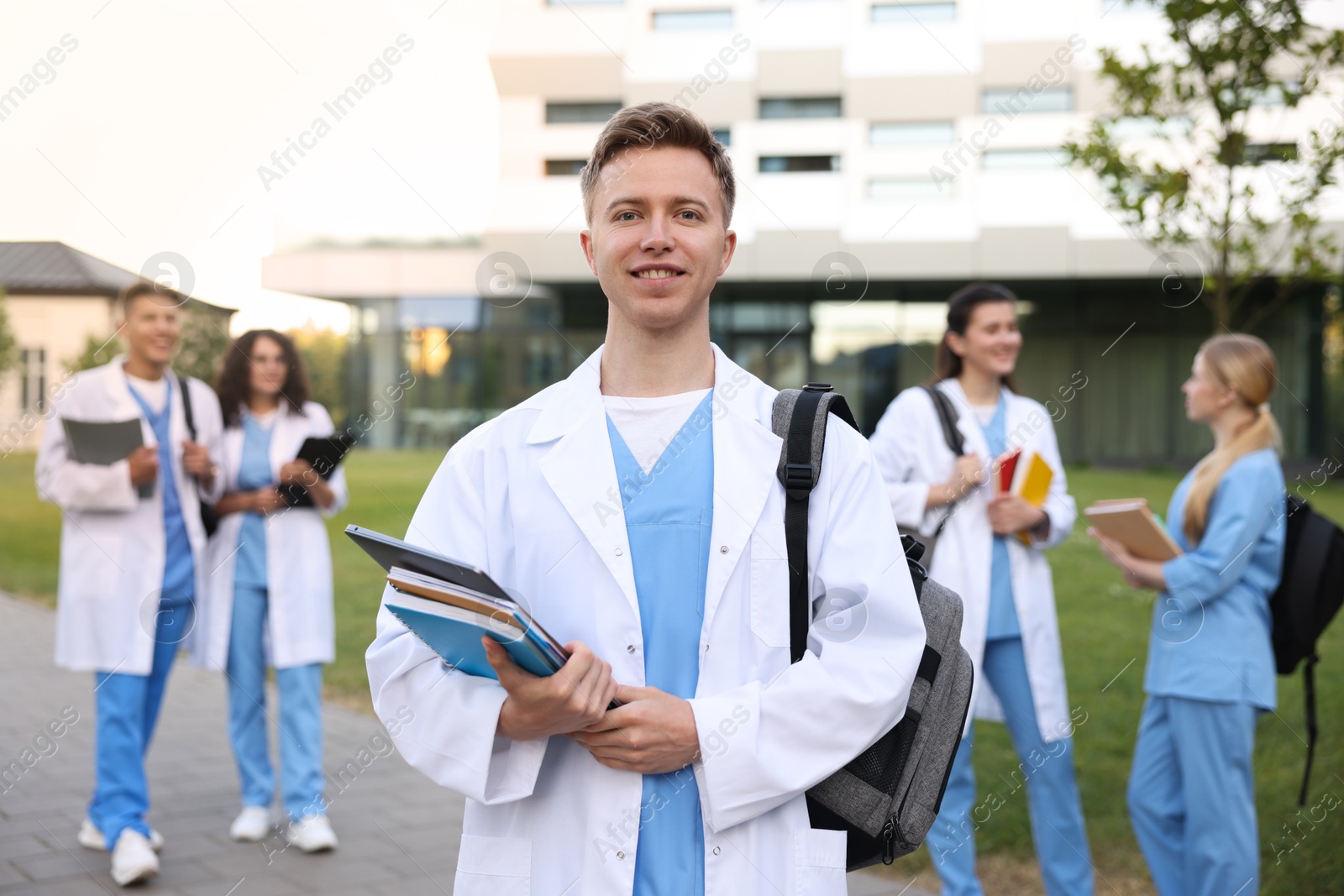 Medical student in uniform with backpack, laptop and notebooks outdoors, selective focus Photo of Medical student in uniform with backpack, laptop and notebooks outdoors, selective focus