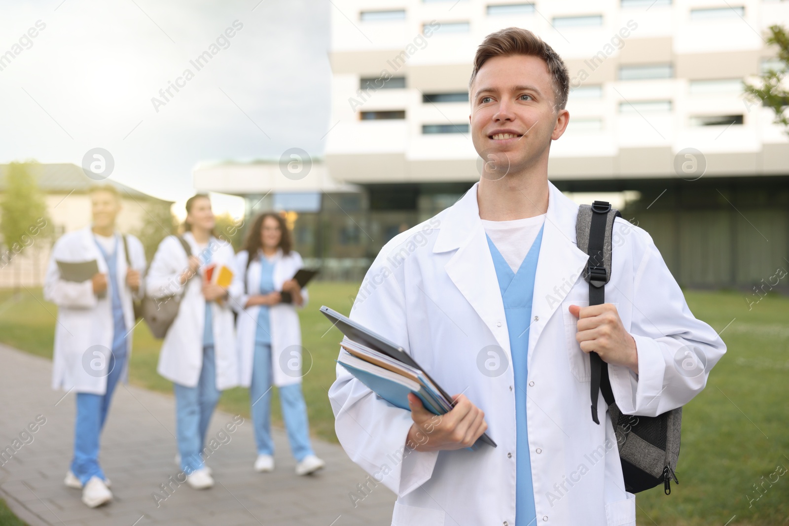 Medical student in uniform with backpack, laptop and notebooks outdoors, selective focus Photo of Medical student in uniform with backpack, laptop and notebooks outdoors, selective focus