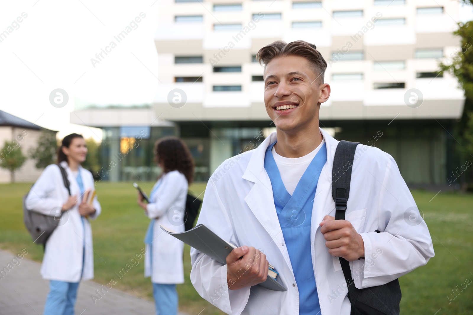 Medical student in uniform with backpack and notebook outdoors, selective focus Photo of Medical student in uniform with backpack and notebook outdoors, selective focus