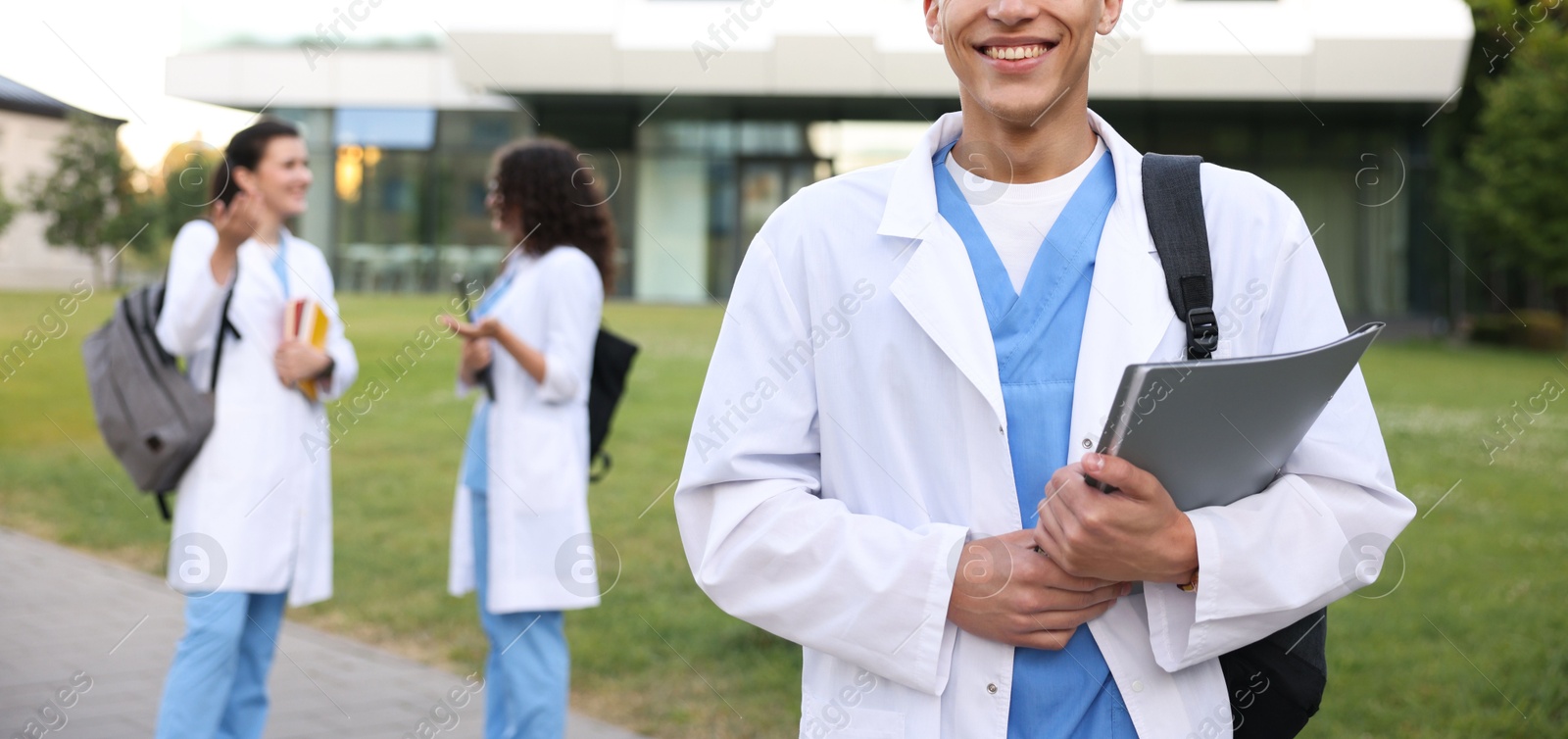 Medical student in uniform with backpack and notebook outdoors, selective focus Photo of Medical student in uniform with backpack and notebook outdoors, selective focus