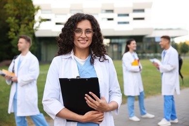 Photo of Medical student in uniform with clipboard outdoors, selective focus