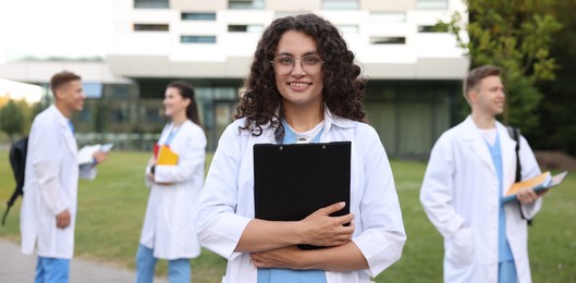 Photo of Medical student in uniform with clipboard outdoors, selective focus