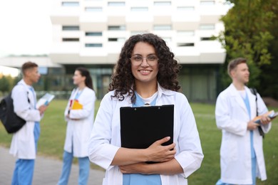 Photo of Medical student in uniform with clipboard outdoors, selective focus