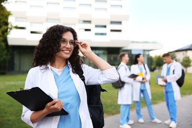 Photo of Medical student in uniform with clipboard outdoors, selective focus