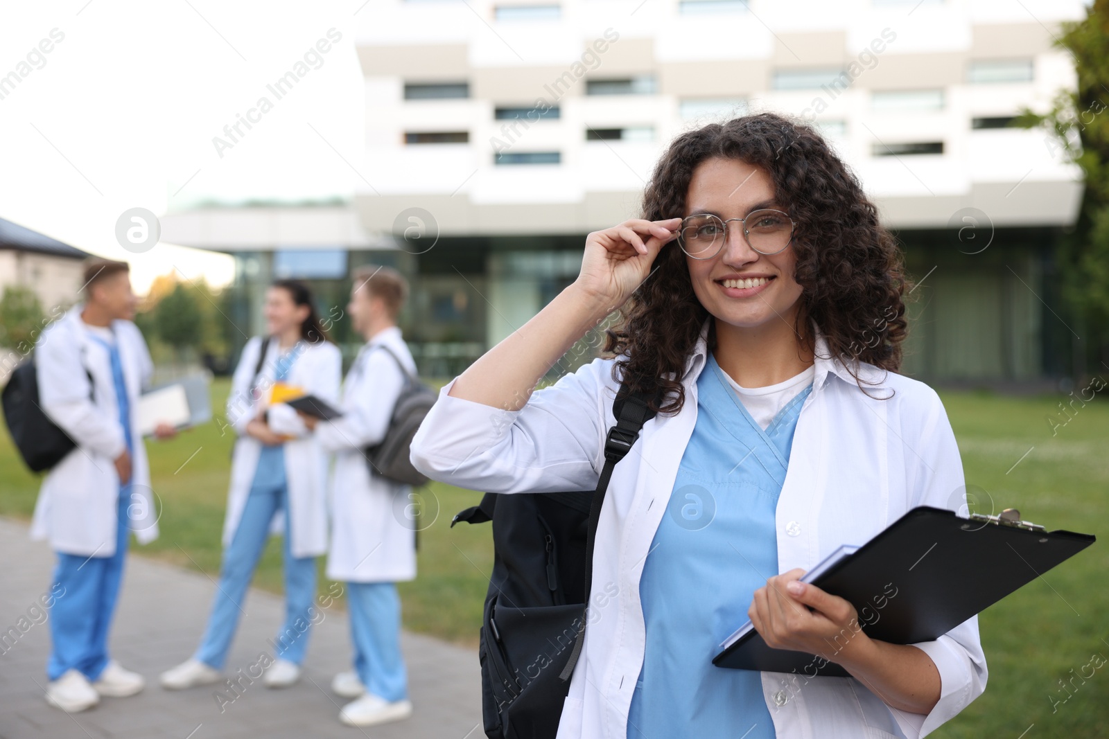 Medical student in uniform with clipboard outdoors, selective focus Photo of Medical student in uniform with clipboard outdoors, selective focus