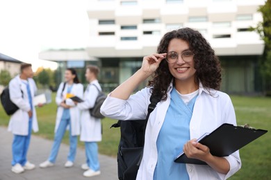 Photo of Medical student in uniform with clipboard outdoors, selective focus