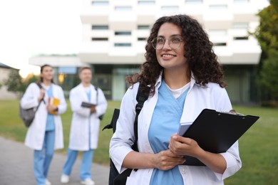 Photo of Medical student in uniform with clipboard outdoors, selective focus
