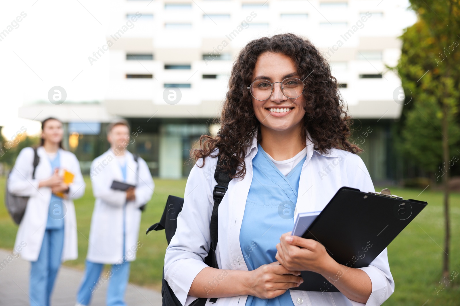 Medical student in uniform with clipboard outdoors, selective focus Photo of Medical student in uniform with clipboard outdoors, selective focus