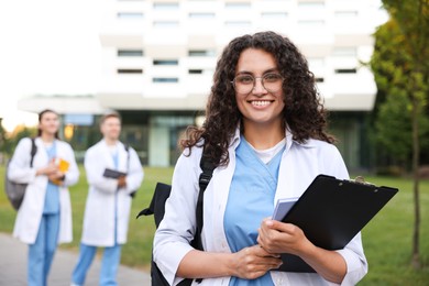 Photo of Medical student in uniform with clipboard outdoors, selective focus