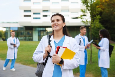 Photo of Medical student in uniform with notebooks outdoors, selective focus
