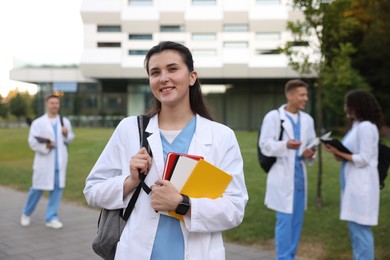 Photo of Medical student in uniform with notebooks outdoors, selective focus