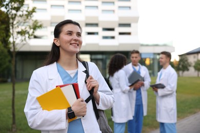 Photo of Medical student in uniform with notebooks outdoors, selective focus