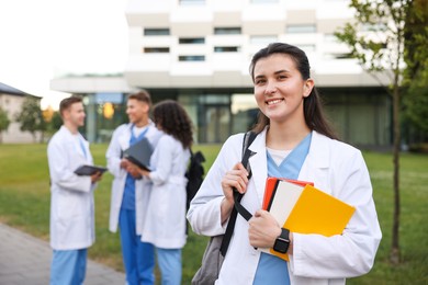 Photo of Medical student in uniform with notebooks outdoors, selective focus