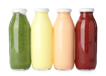 Photo of Superfood. Different tasty smoothies in glass bottles isolated on white