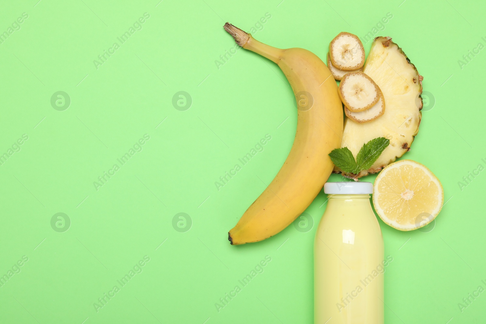 Photo of Superfood. Tasty smoothie in glass bottle and ingredients on green background, flat lay. Space for text